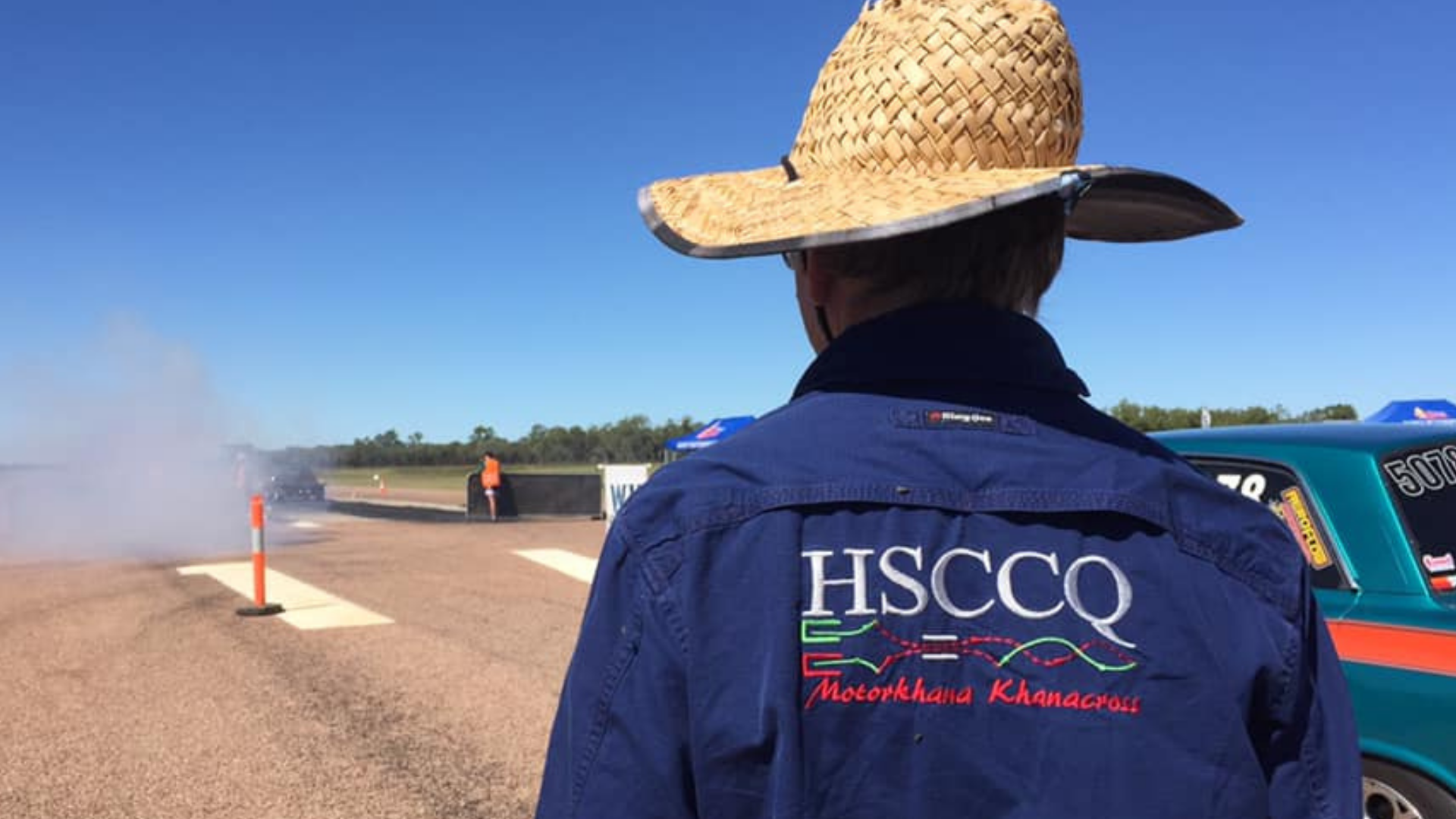 Member wearing an HSCCQ shirt looks at car participating in motorsport event